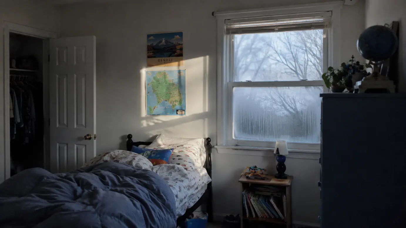 A child's bedroom in early morning light with faint condensation on the window